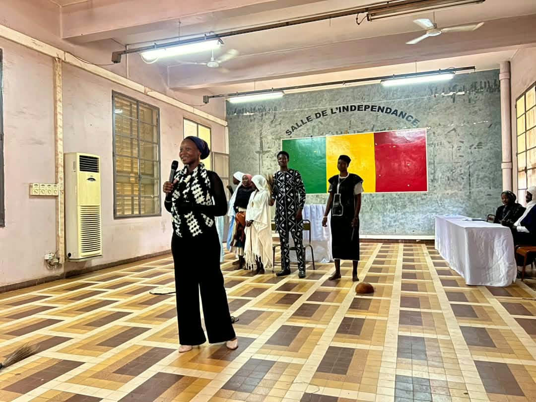 Une animatrice s’exprime au micro devant un groupe de jeunes réunis dans la Salle de l’Indépendance