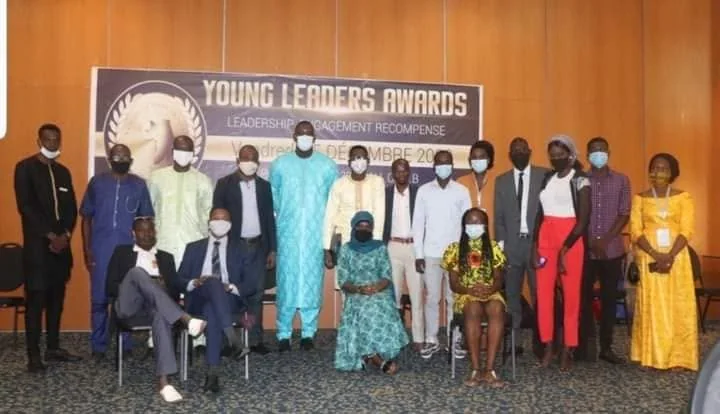 Groupe de dix-sept participants en tenues formelles posant devant la bannière Young Leaders Awards, leadership, engagement récompensé